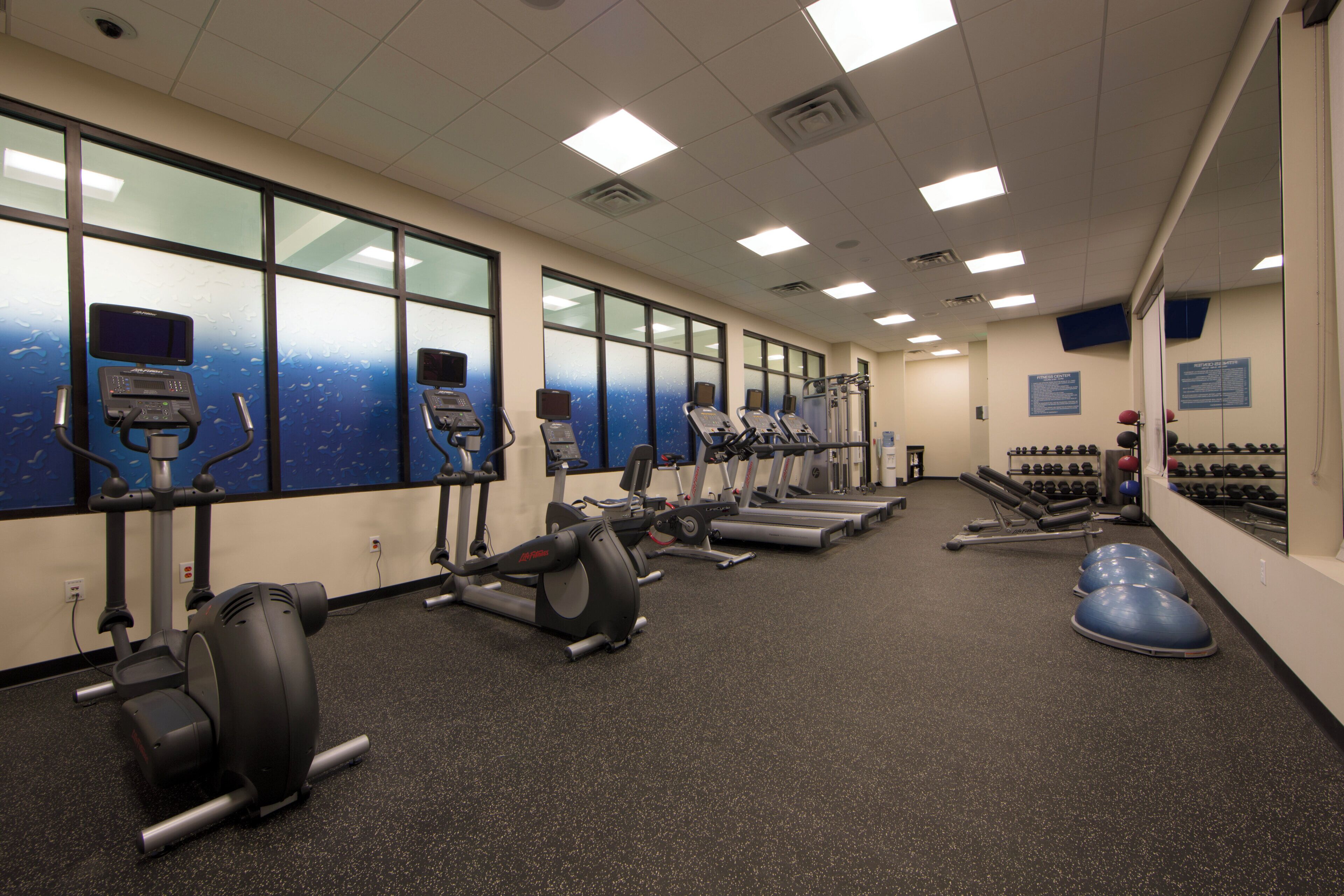 A gym with treadmills, elliptical machines, and weightlifting equipment.