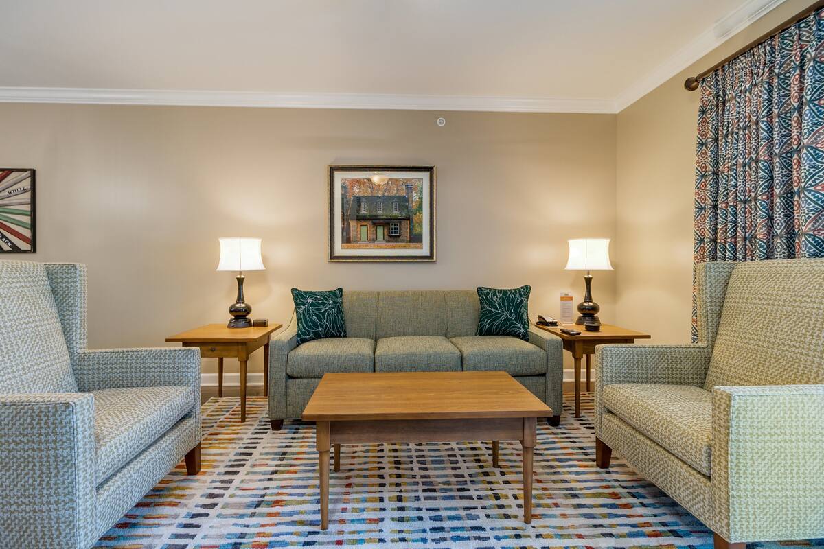 A living room with a sofa, two armchairs, a coffee table, and two lamps.