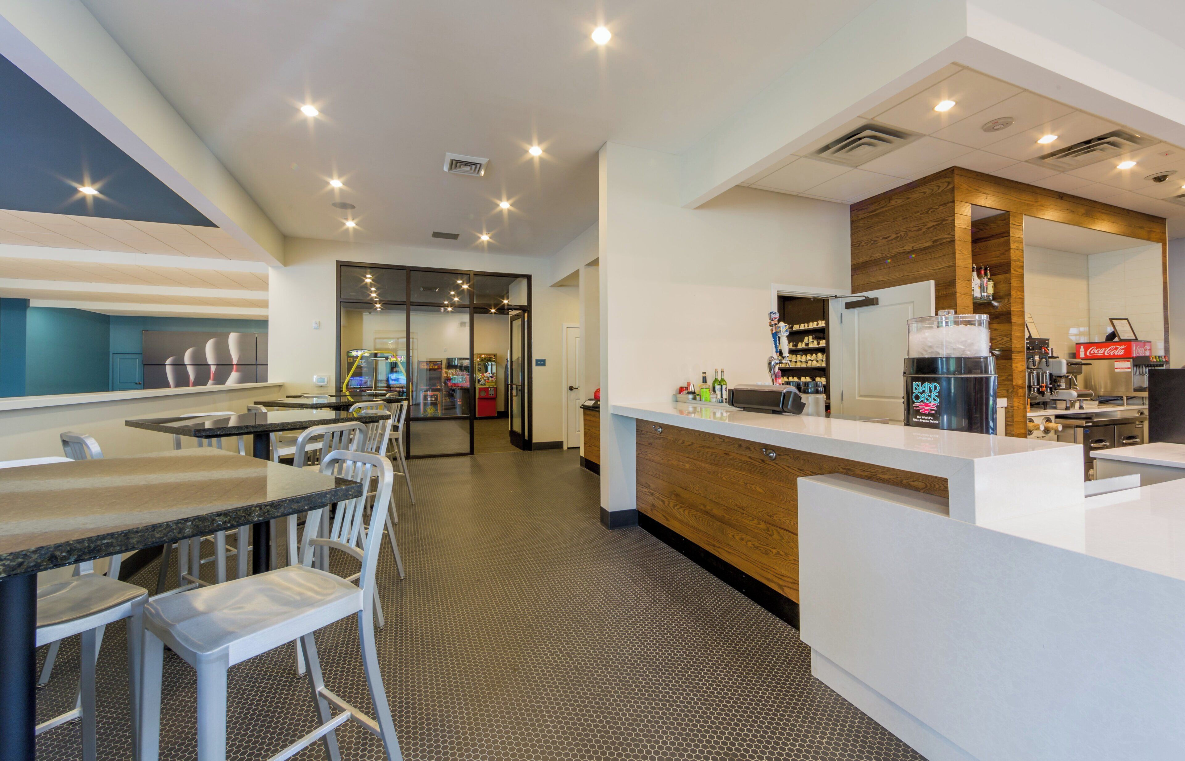 A modern hotel lobby with a reception desk, seating area, and a view of the bar area.