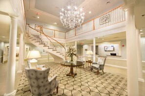A spacious lobby with a grand staircase, a chandelier, and a reception desk. - Holiday Inn Club Vacations Williamsburg Resort by IHG (Williamsburg)