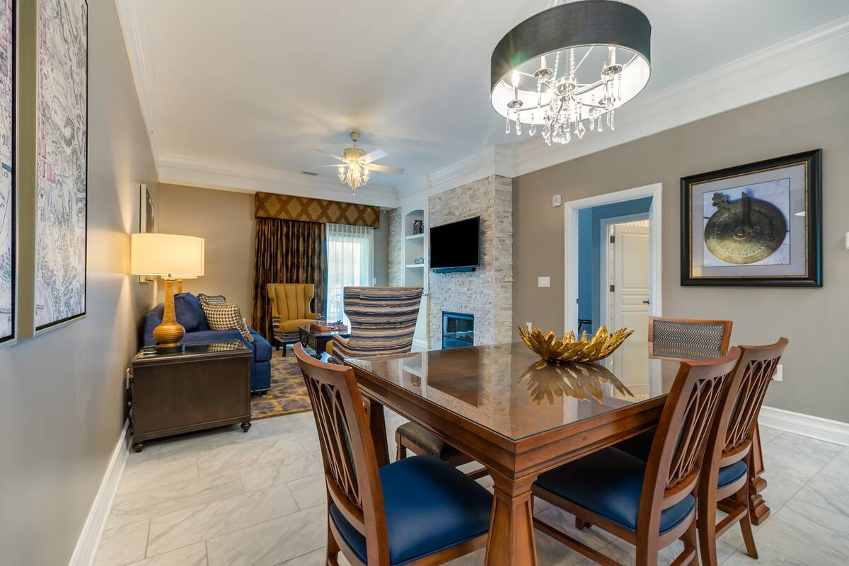 A dining area with a wooden table, blue upholstered chairs, and a chandelier.