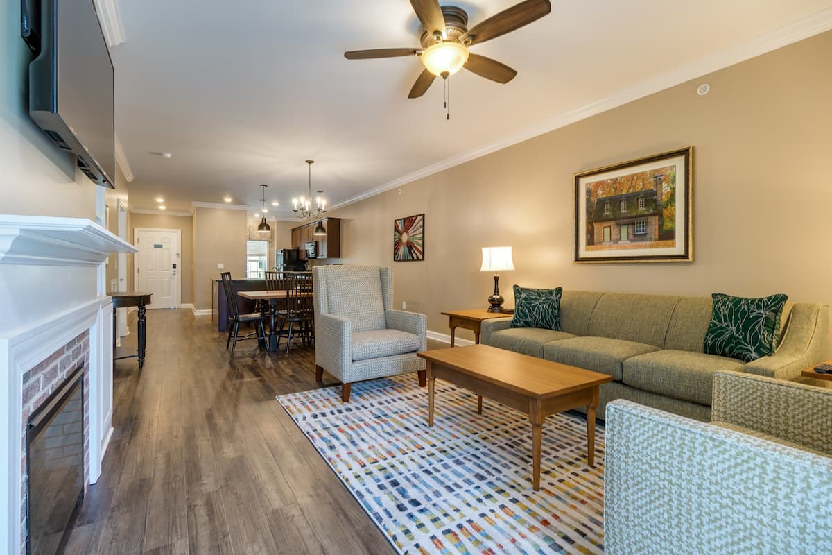 A living room with a fireplace, a sofa, a coffee table, and a patterned rug.