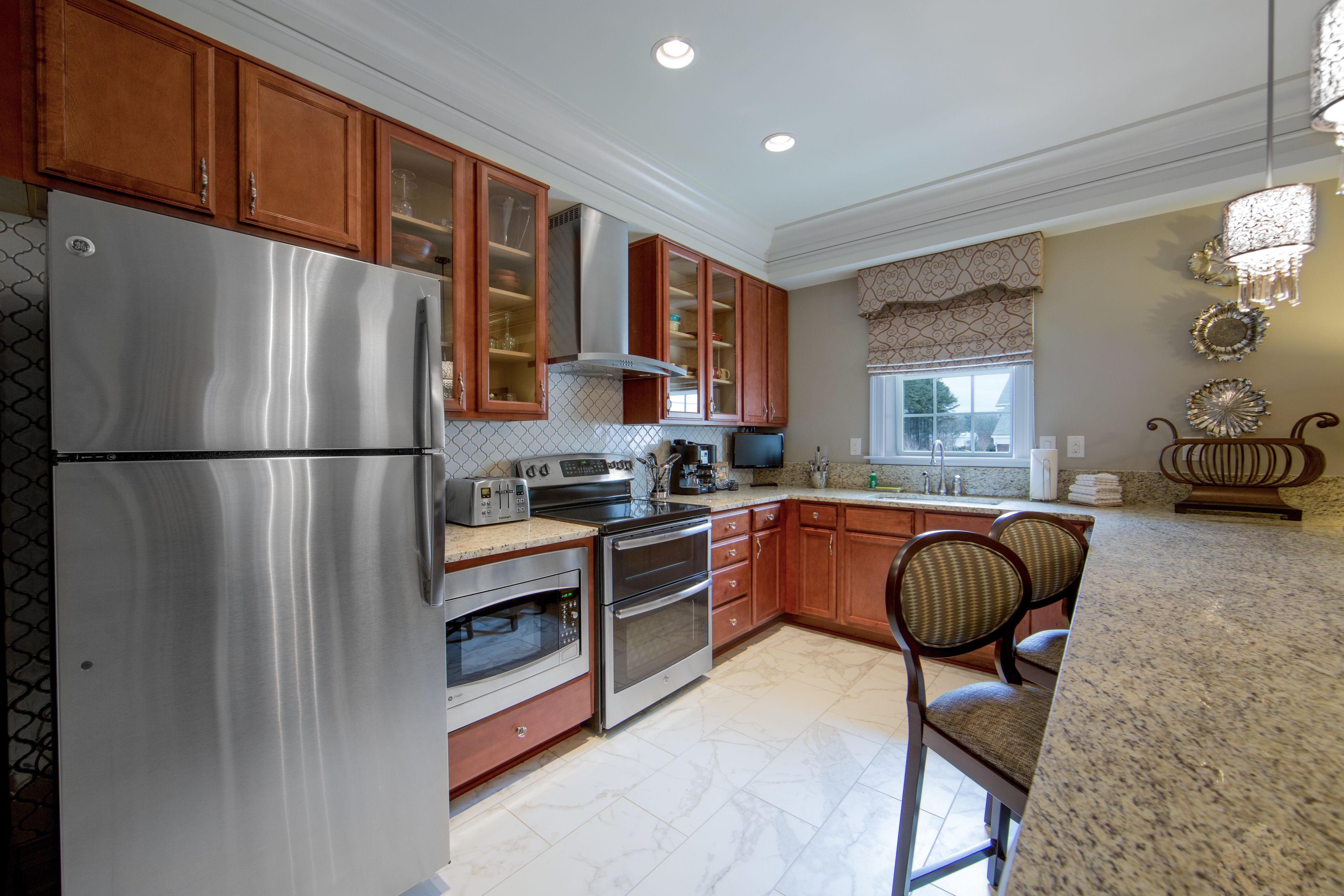 A kitchen with stainless steel appliances, wooden cabinets, and a granite countertop.