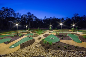Un campo de golf al anochecer con senderos iluminados y amplios espacios verdes.