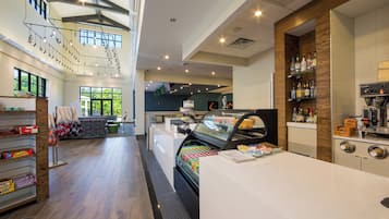 A modern cafe interior with a central counter, seating area, and a view of the outdoors.