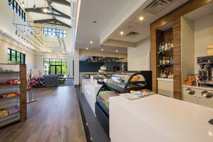 Un interior de cafetería moderna con un mostrador central, zona de estar y vistas al exterior.