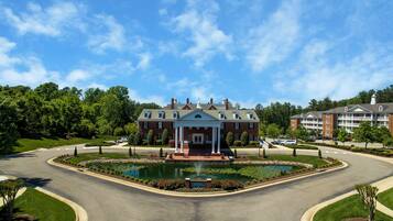A large brick building with a central pavilion, a landscaped pond, and a well-maintained lawn.