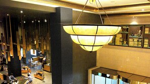 A spacious lobby with a modern chandelier, seating areas, and a Starbucks. - Grand Hotel (Daegu)