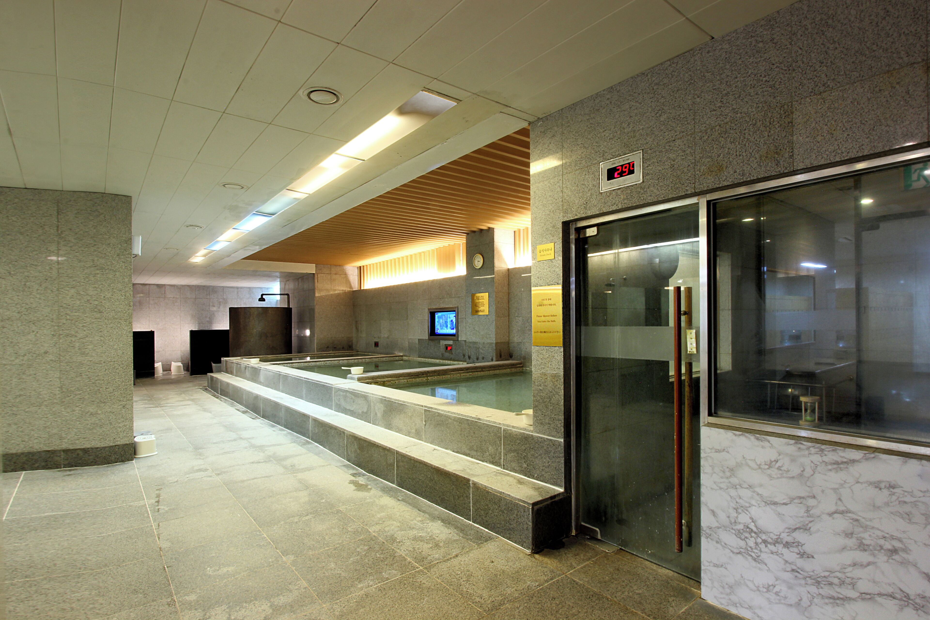 A modern lobby with a reception desk, a digital clock, and a glass elevator.