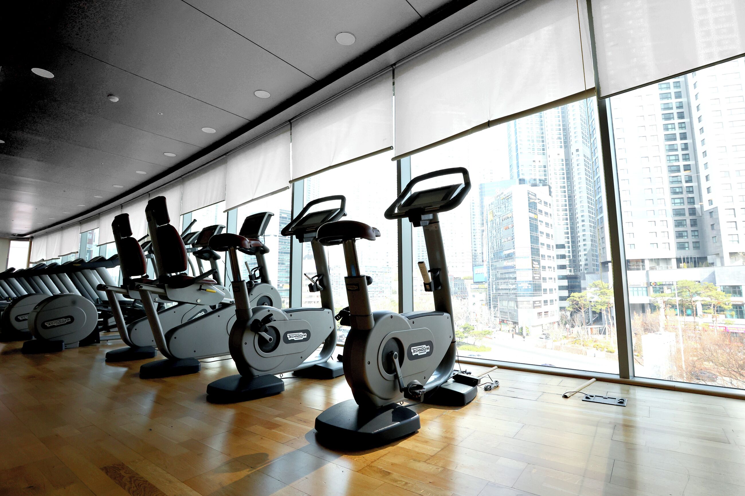 Una palestra con attrezzature per l'allenamento e ampie finestre con vista sulla città.