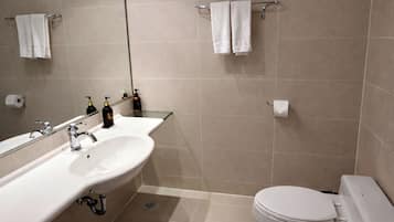A modern bathroom with a large sink, mirror, and toilet.