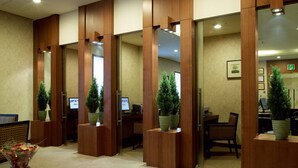A reception area with wooden partitions, multiple computer workstations, and potted plants. - Grand Hotel (Daegu)