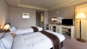 Een hotelkamer met twee bedden, een bureau met een televisie, een lamp en een kledingkast.