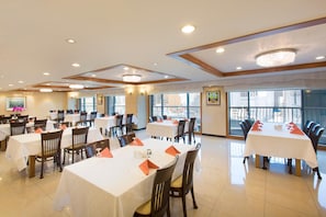 A large dining area with multiple tables and chairs, high ceilings with recessed lighting, and large windows offering views of the city. - Libero Hotel (Busan)