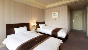 Een hotelkamer met twee bedden, een nachtkastje met een lamp en een lijst aan de muur.