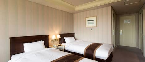 Una habitación de hotel con dos camas, una mesita de noche con lámpara y un cuadro enmarcado en la pared.