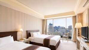 A hotel room with two beds, a desk, a TV, and a view of the city. - Libero Hotel (Busan)