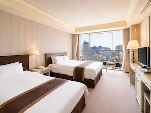 A hotel room with two beds, a desk, a TV, and a view of the city. - Libero Hotel (Busan)