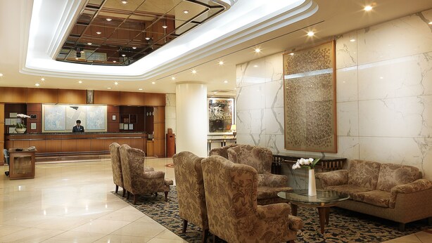A modern lobby with a reception desk, seating area, and a large mirror. - Hotel Paragon (Busan)