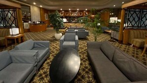 A spacious lobby with grey sofas, a large round table, and a reception desk. - Hotel Paragon (Busan)