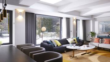 A modern living room with a sofa, armchairs, a coffee table, and a dining area.