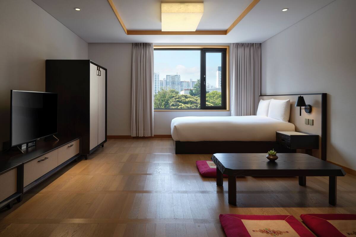 Een moderne hotelkamer met een groot bed, een televisie, een bureau en uitzicht op de stad.