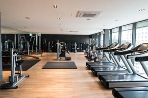 A gym with treadmills, weight machines, and a mirror wall.