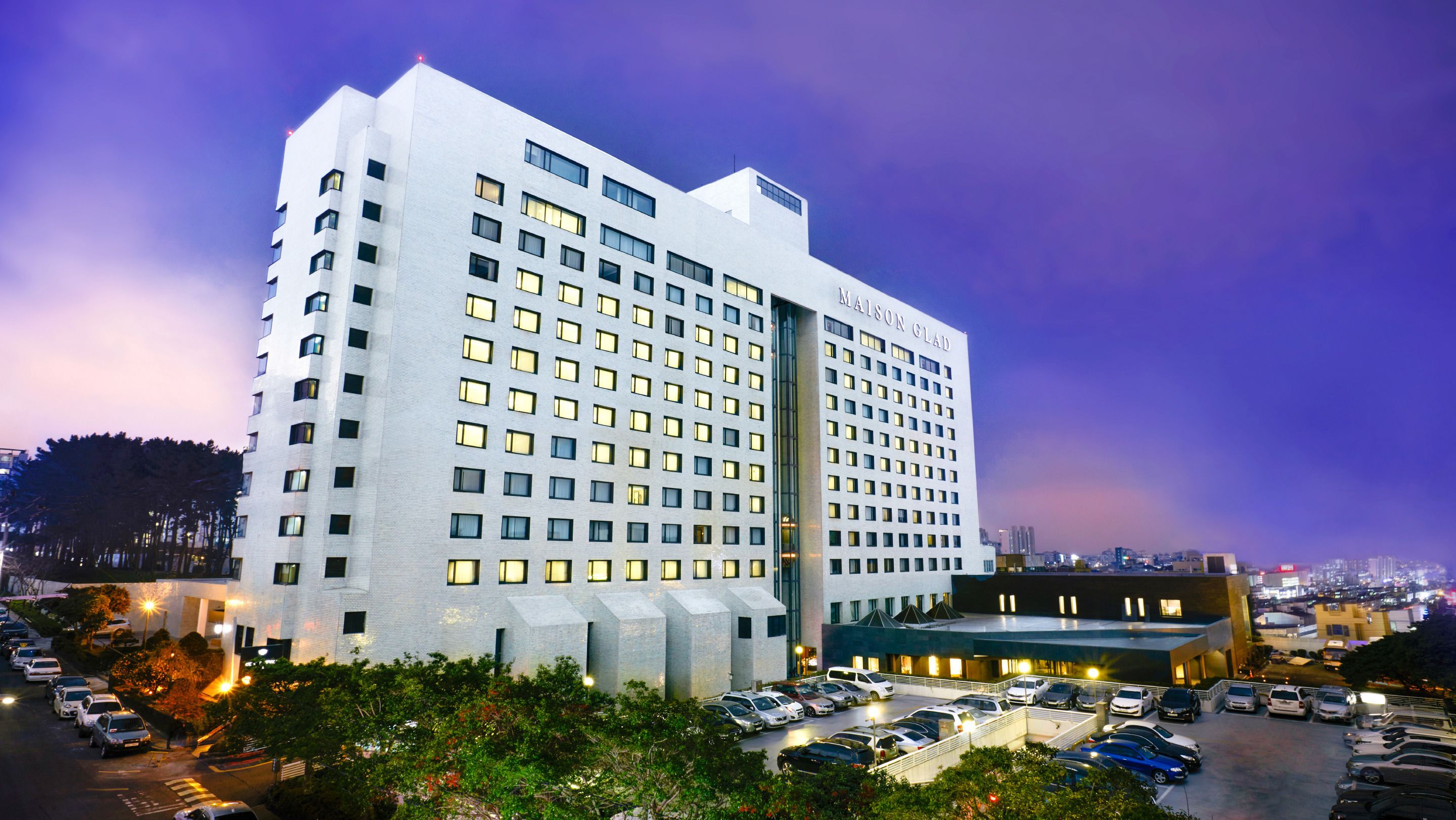 A multi-story hotel with a modern design, featuring a large parking lot in front.