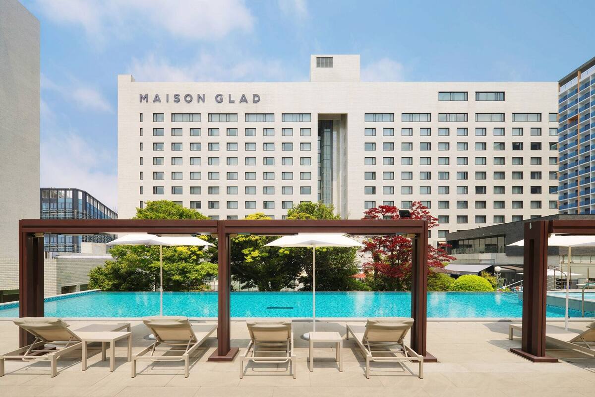 Een hotel genaamd MAISON GLAD met een zwembad op het dak, inclusief ligbedden en parasols.