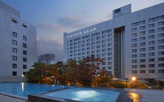 Un hotel moderno con zona de piscina, que presenta un edificio grande con el nombre 'MAISON GLAD' bien visible.