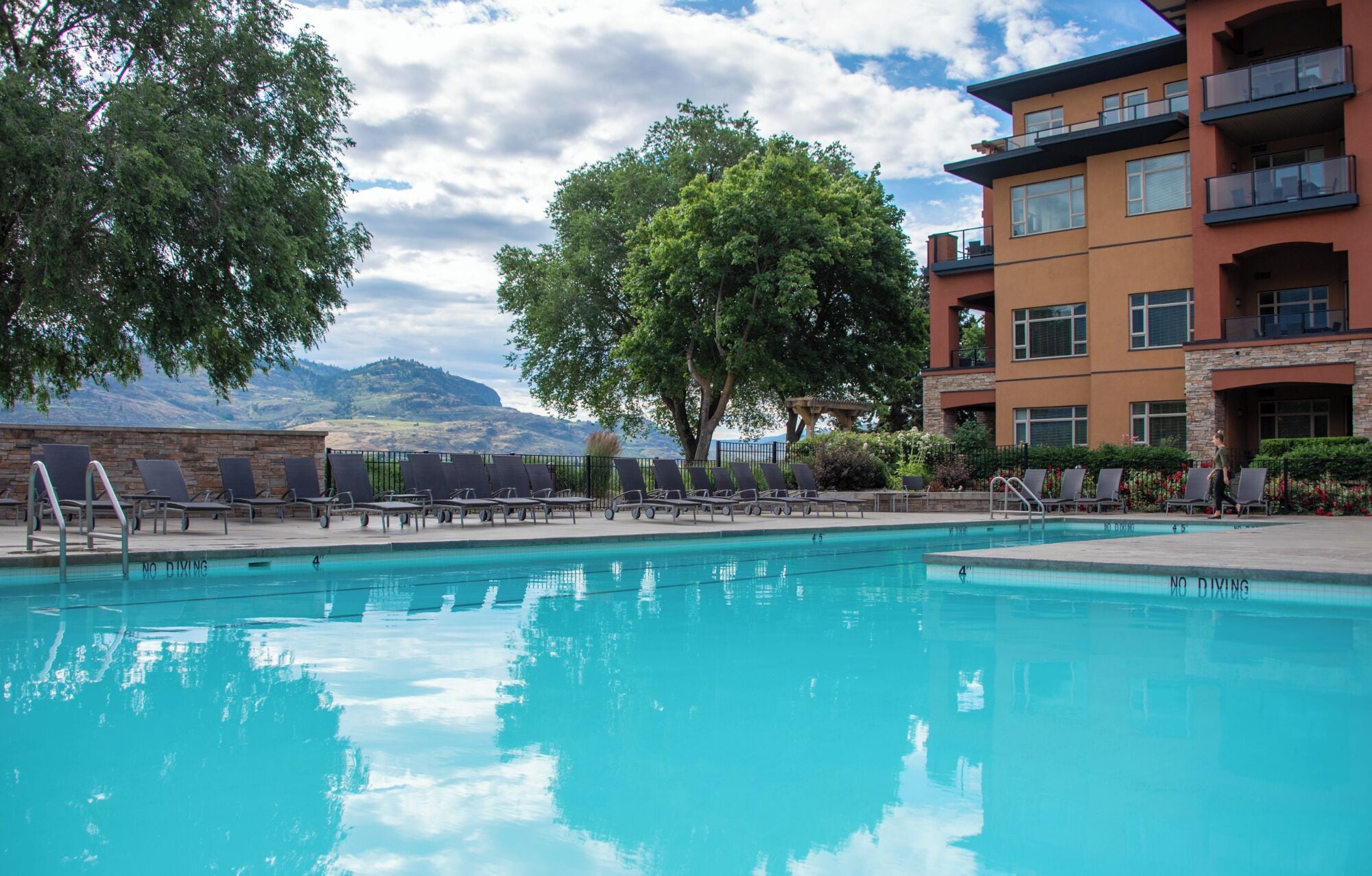 A swimming pool with lounge chairs and a view of mountains.