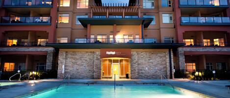 Ein Hotel mit Pool, mehreren Balkonen und einer steinernen Fassade.