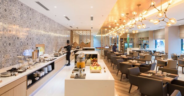 Enjoy a meal at our restaurant, which offers a variety of food and drink options in a clean and contemporary setting with a buffet area, seating, and a bar.