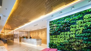 A modern lobby with a reception desk, a large green wall with plants, and a red and yellow sectional sofa. - Hilton Garden Inn Kuala Lumpur Jalan Tuanku Abdul Rahman North (Kuala Lumpur)