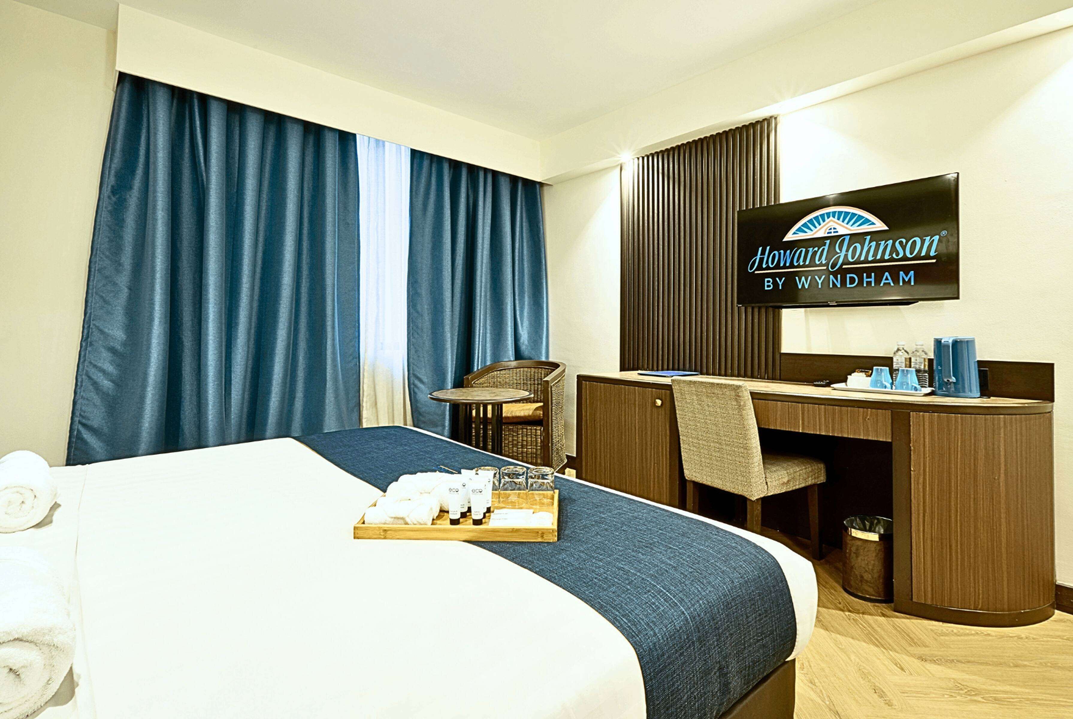 Een hotelkamer met een bed, een bureau, een stoel, een televisie en een dienblad met toiletartikelen.