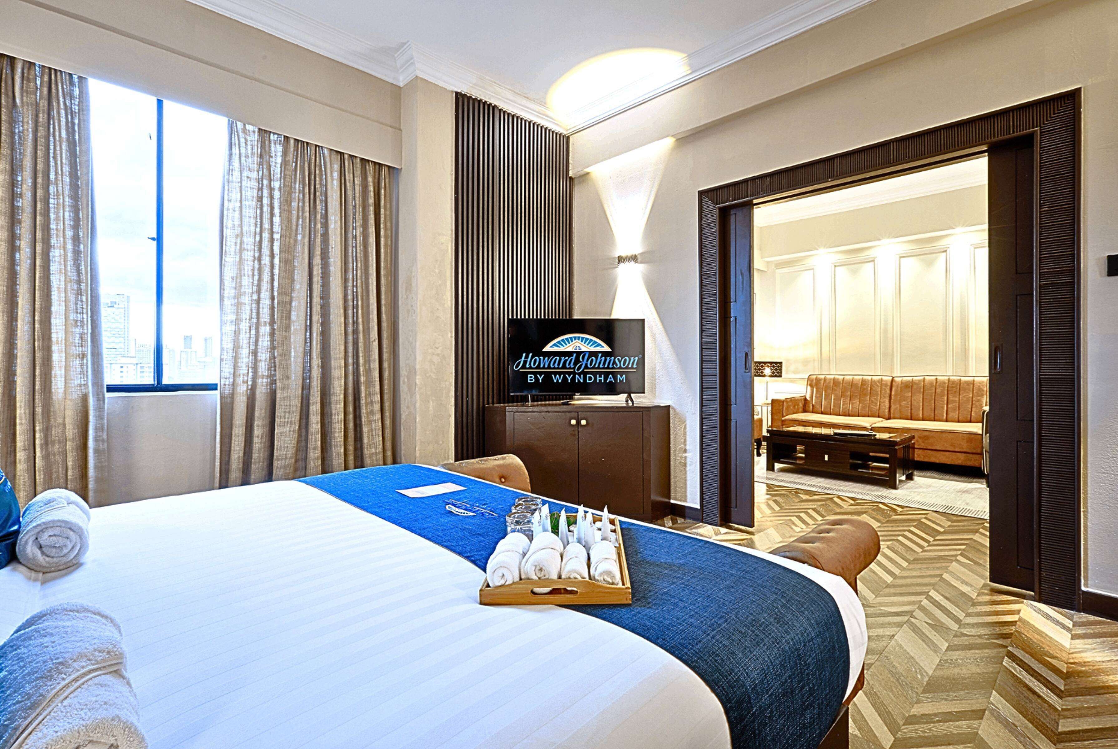 A hotel room with a large bed, a television, a desk, and a view of the city.