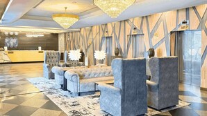 A lobby with a reception desk, a guest lift, and a seating area with grey upholstered sofas and armchairs. - Howard Johnson By Wyndham Kuala Lumpur 118 (Kuala Lumpur)