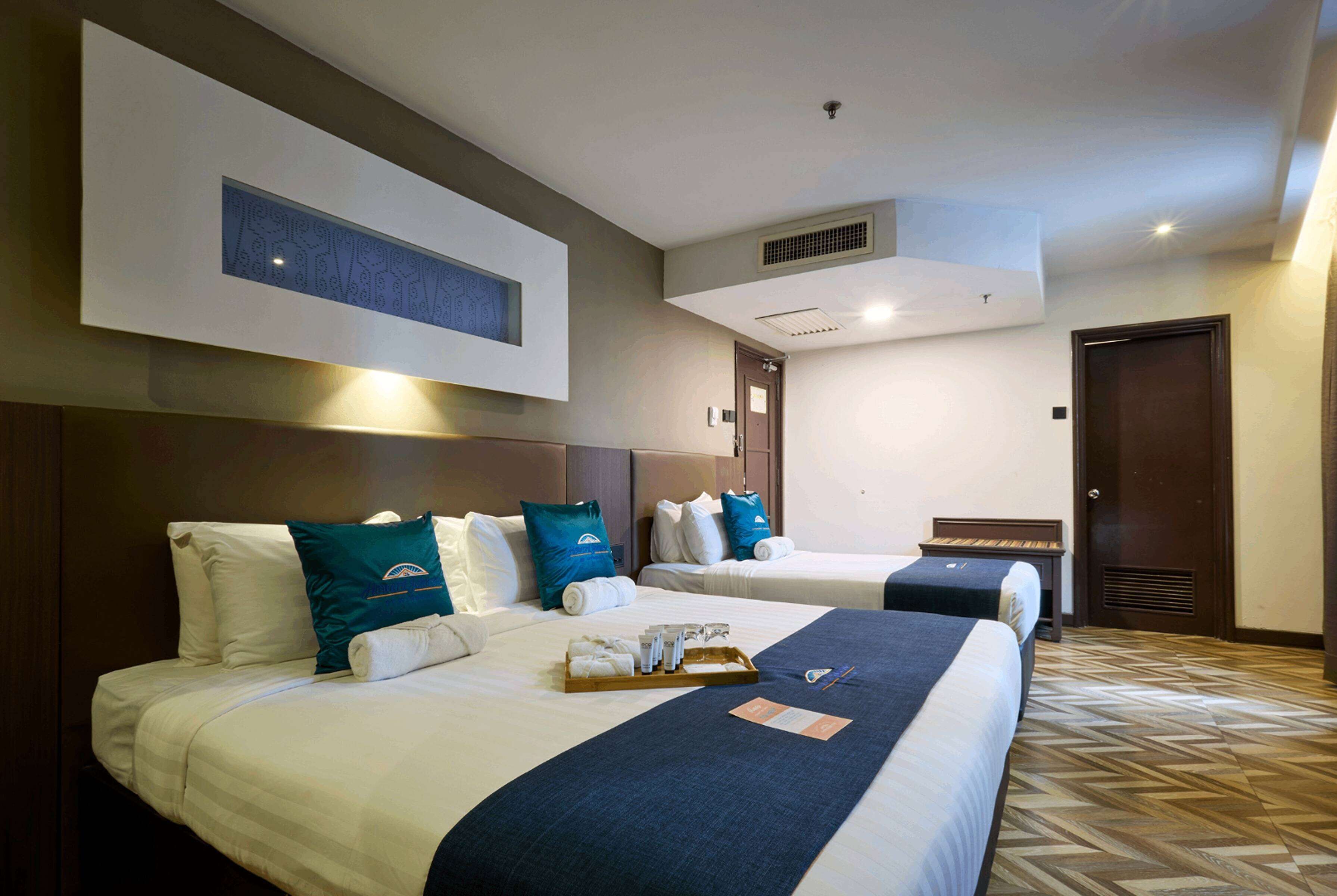 A hotel room with two beds, a large artwork on the wall, and a wooden floor.