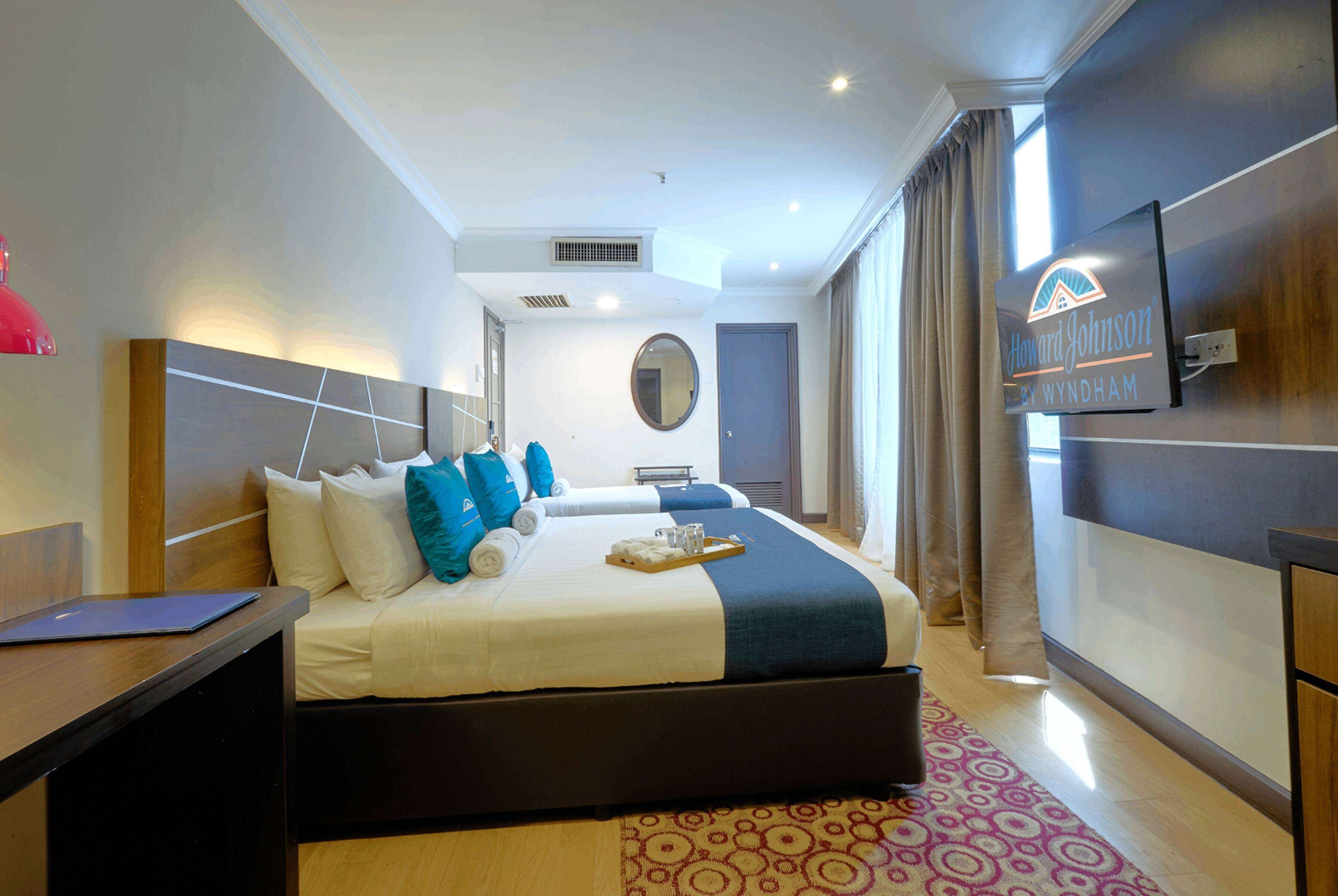 A hotel room with a bed, a desk, a TV, and a bathroom.