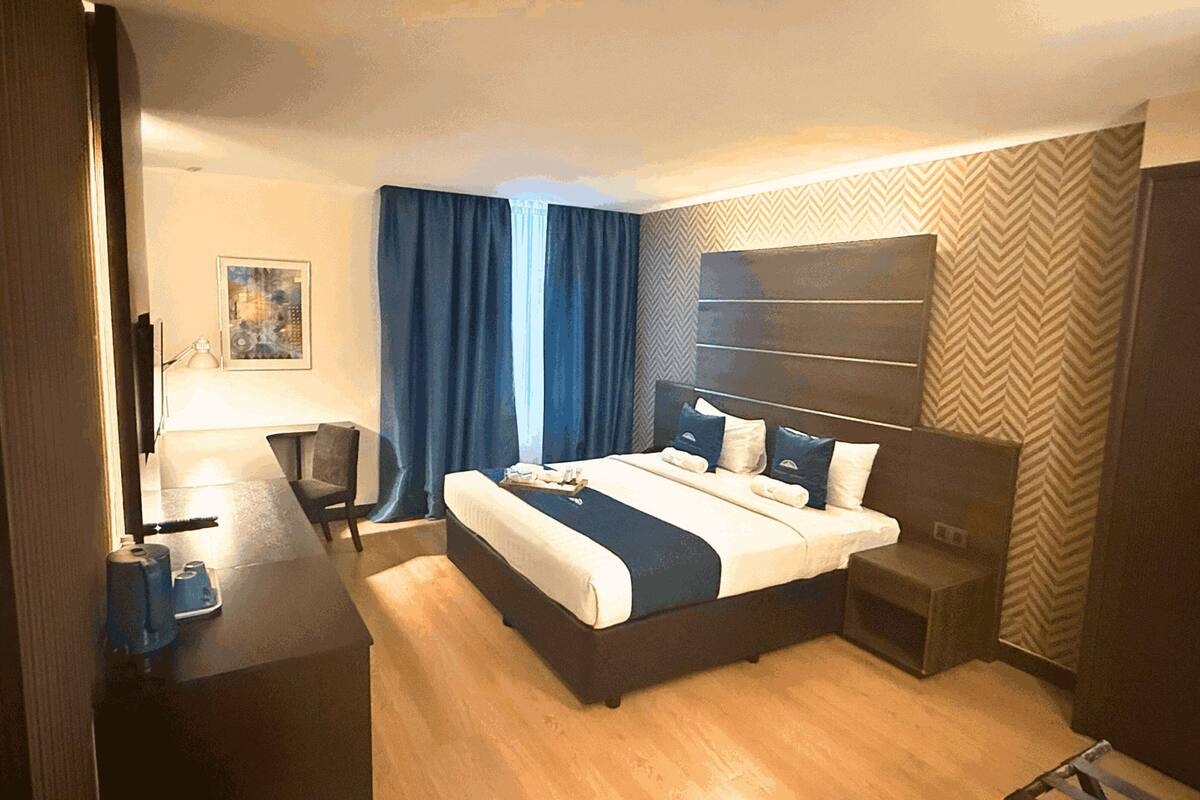 A modern hotel room with a large bed, a desk, and a chair.