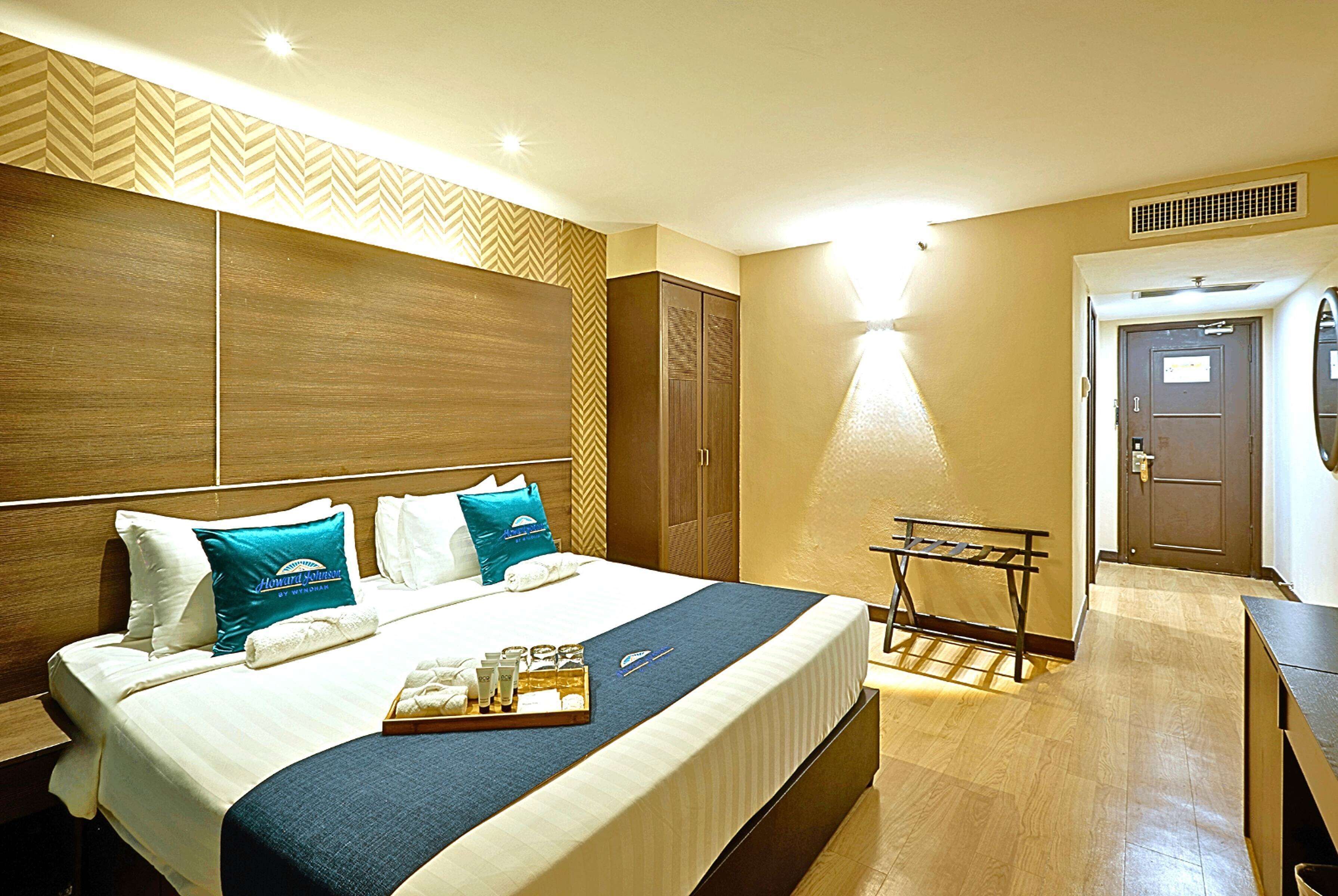 A hotel room with a large bed, a bedside table, a mirror, and a wardrobe.