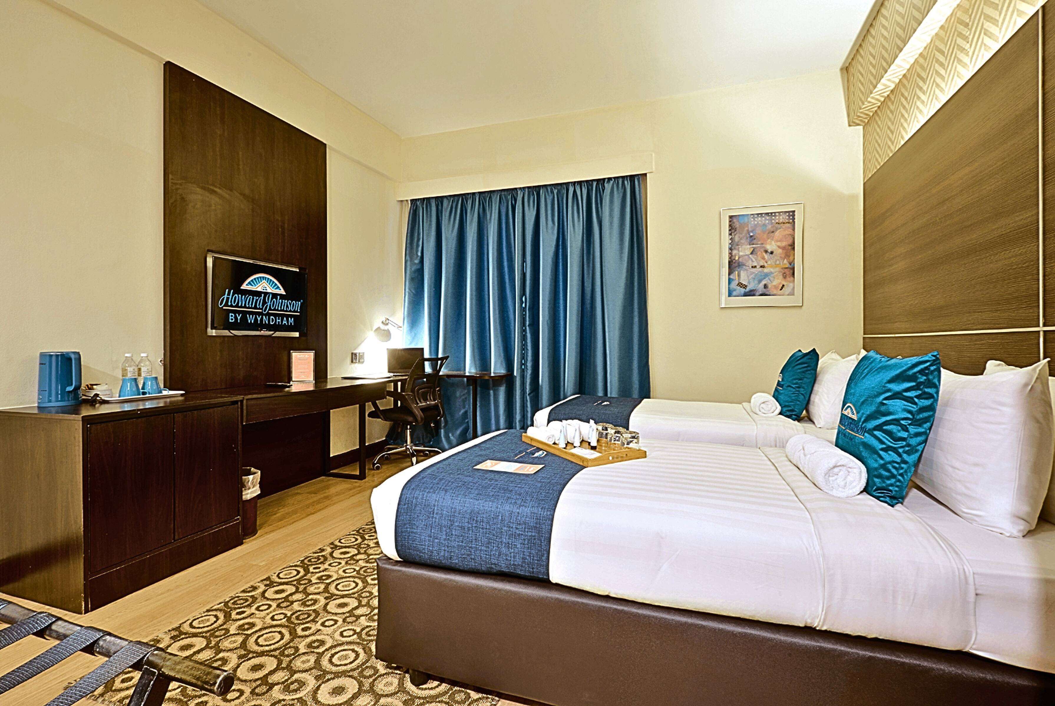 Une chambre d’hôtel avec un lit, un bureau, une chaise, une télévision et un tableau au mur.