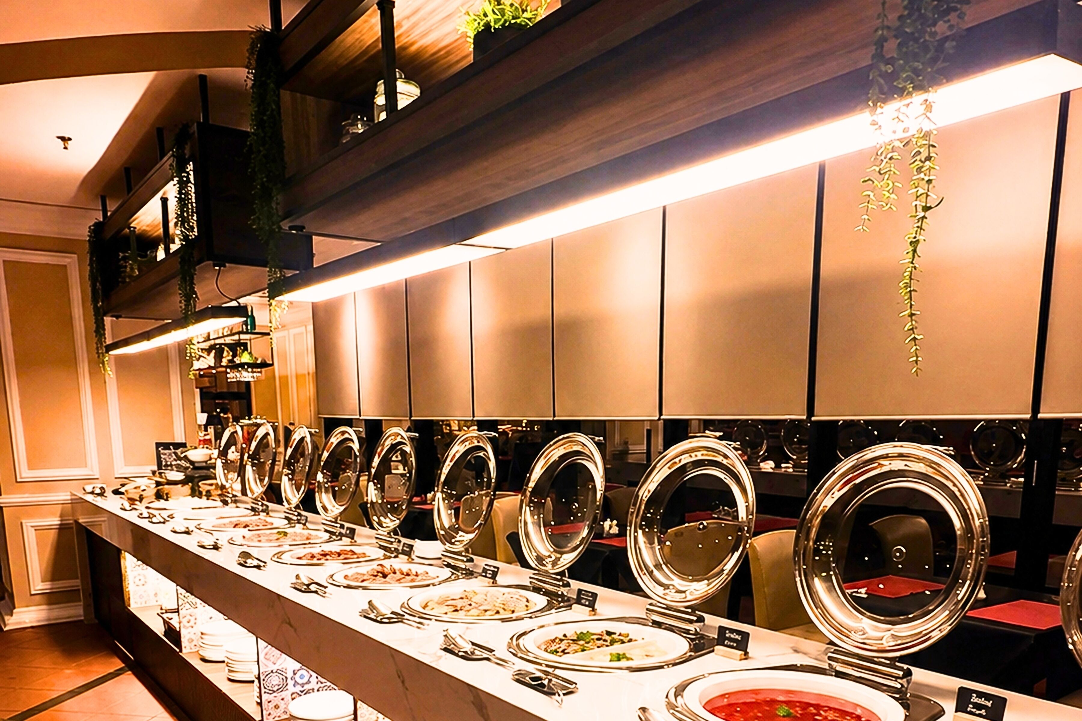 A buffet setup with multiple serving stations, each with a large, round, reflective serving dish.