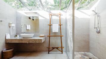 Un baño moderno con un espejo grande, un toallero de madera, un lavamanos y una zona de ducha.