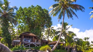 A resort with wooden buildings, palm trees, and a beach. - Sinalei Reef Resort & Spa (Siumu)