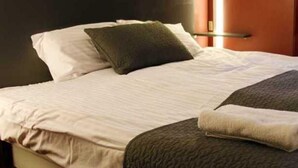 A neatly made bed with white linens and a dark gray throw blanket.