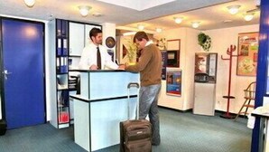 A reception desk with a blue door, a counter, and a man standing beside it.