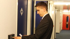 A man in a suit interacting with a door control panel in a hallway with blue doors and a number 325 sign.