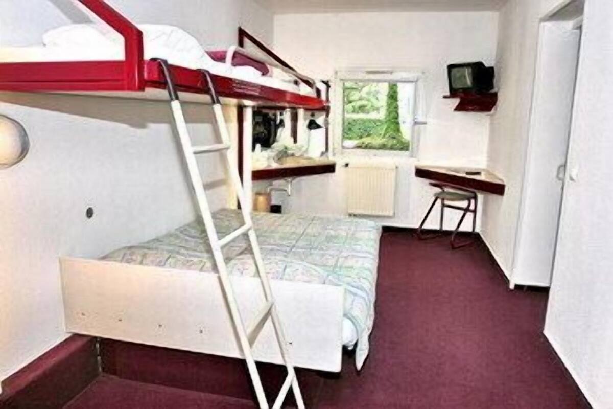 A compact room with bunk beds, a desk, a chair, and a television.