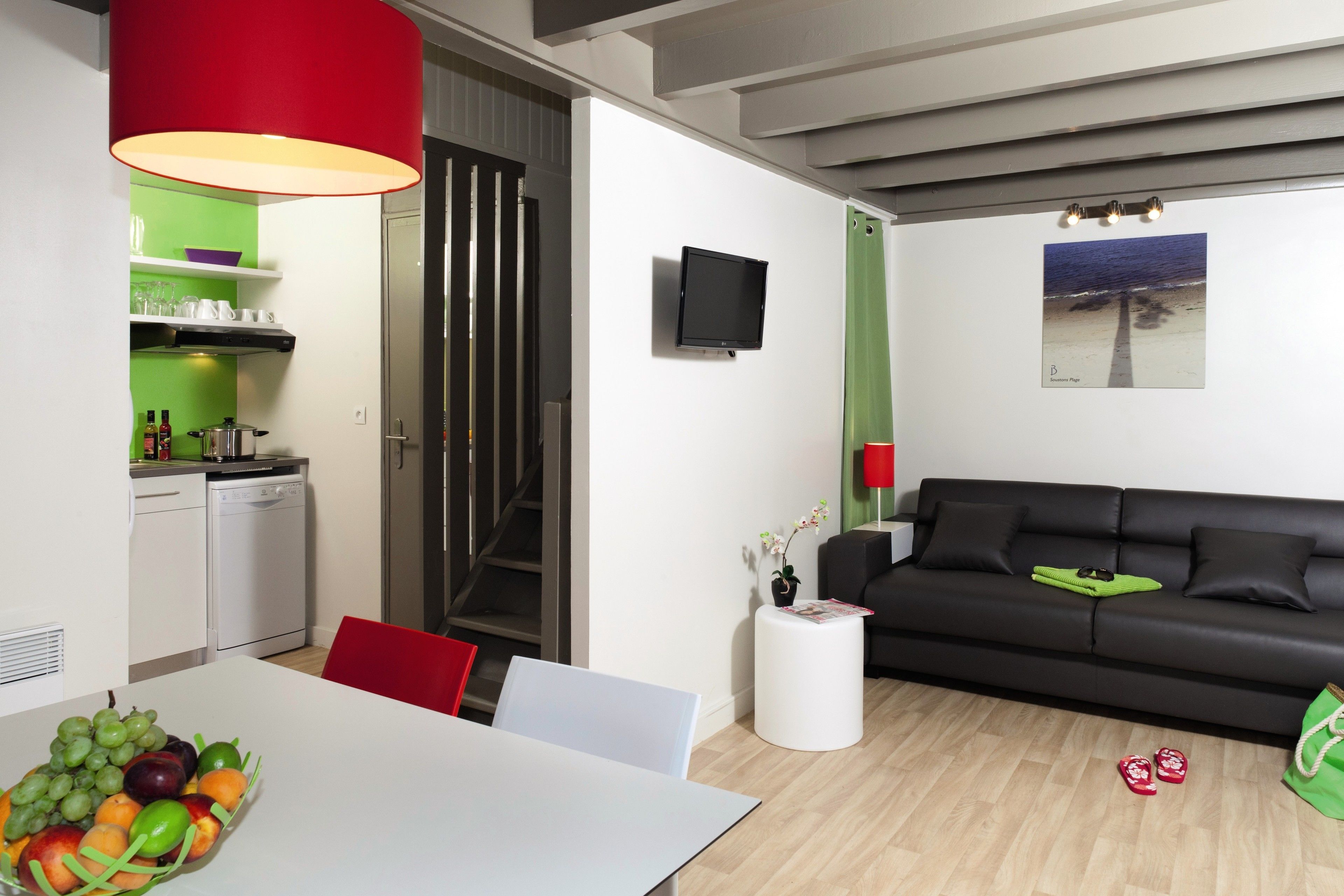 Un espace de vie moderne comprenant un coin repas, une cuisine et un canapé noir.